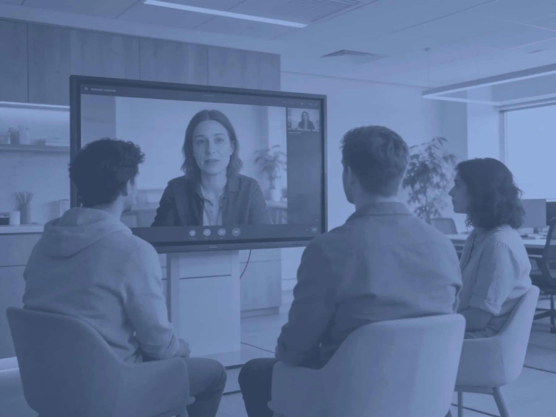 A team in a Scandinavian office on a video call with a remote colleague